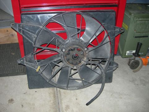 1985 Ford Bronco - Radiator fan assembly shown in a garage setting with tools and storage containers in the background.
