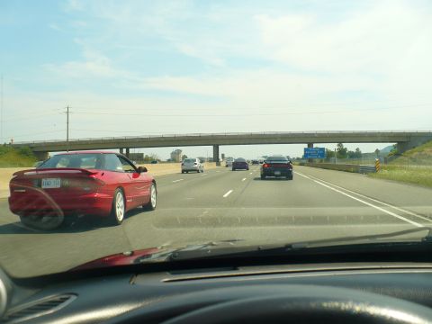 1993 Ford Probe - A red 1993 Ford Probe is seen from behind on a sunny day on the highway.