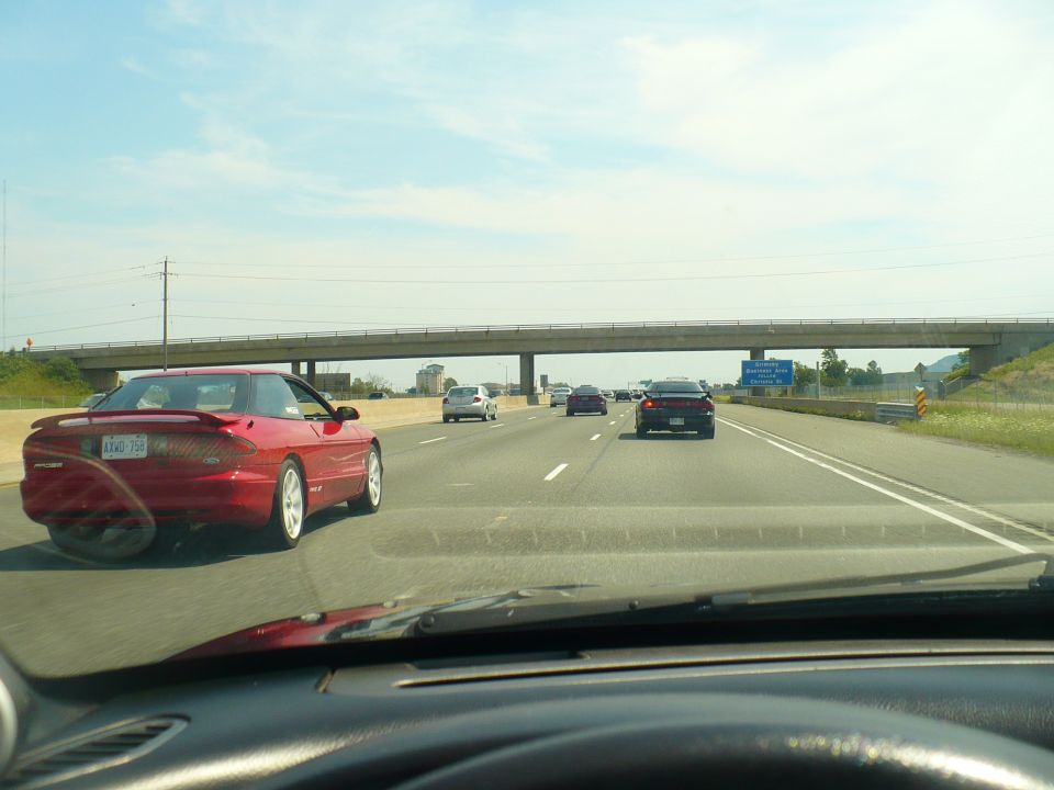 Red 1993 Ford Probe driving on a highway, seen from another car