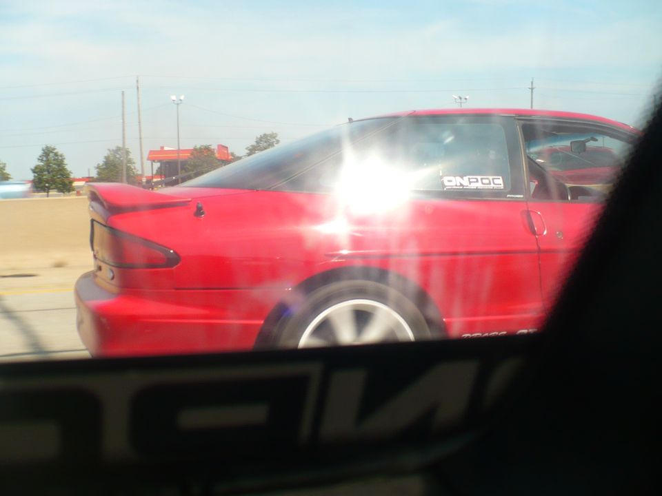 Red 1993 Ford Probe coupe, side view, driving on a sunny day