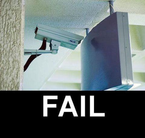 1988 Mercury Grand Marquis - A security camera is mounted on a bracket next to a large, dark, curved object. The word "FAIL" is displayed in large white letters on a bl…