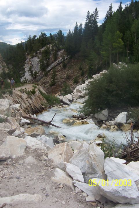 1996 Ford Bronco - A fast-flowing stream cuts through a rocky canyon, with trees on the slopes above.