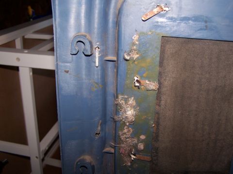 1986 Ford Bronco - Close-up of a blue door panel interior showing rust and debris around metal attachment points.