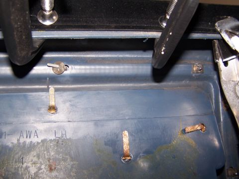 1986 Ford Bronco - Close-up of a blue interior door panel, showing clips and stamped text 'AWA LH'.