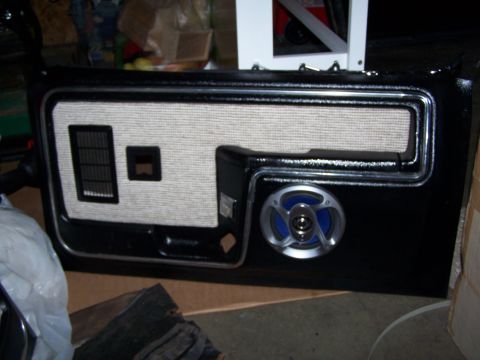1986 Ford Bronco - A black car door panel with a fabric insert and aftermarket speaker is shown.