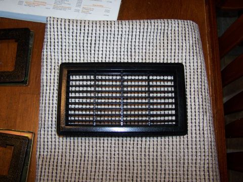 1986 Ford Bronco - A close-up of a black air vent grille, likely a car part, resting on a striped cloth.