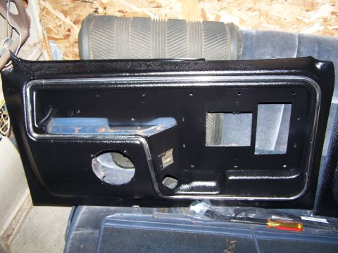 1986 Ford Bronco - A black door panel with chrome trim and cutouts for a speaker and window crank is shown.