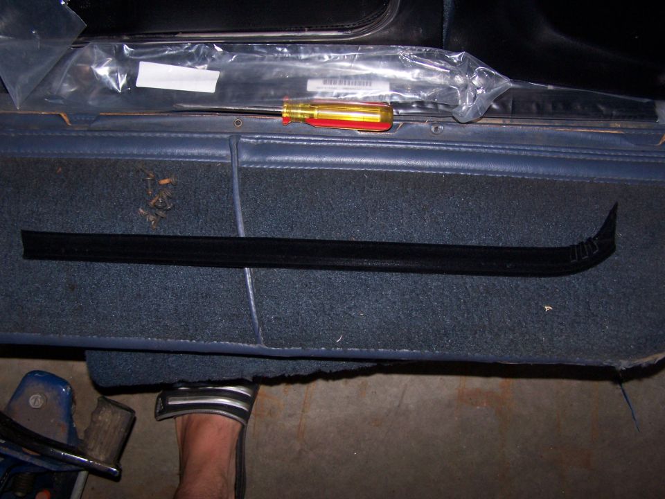 Black door trim piece and screwdriver on blue interior carpet