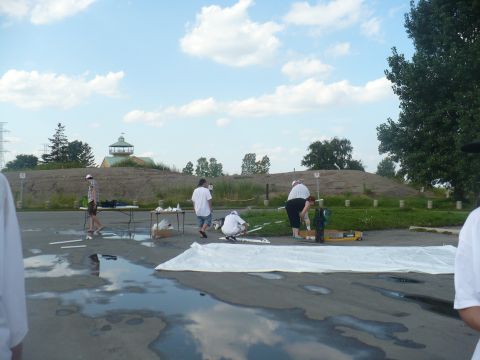 1993 Ford Probe - Several individuals are engaged in an activity around a large white sheet laid out on a wet, reflective asphalt ground.