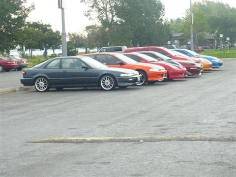 1993 Ford Probe - Multiple vehicles are parked in a lot, with a dark coupe in the foreground.