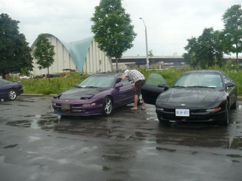 1993 Ford Probe - Two 1993 Ford Probes are parked on a wet surface, with a person interacting with one of them.