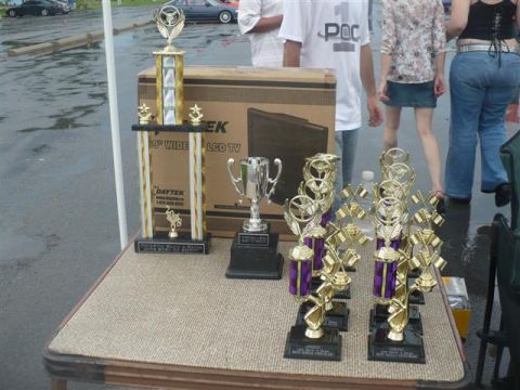 1993 Ford Probe - A collection of trophies sits on a table next to a boxed TV, with people in the background.
