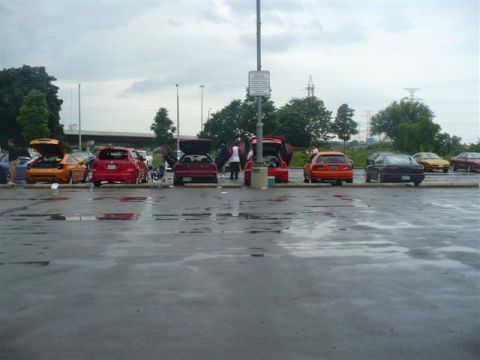 1993 Ford Probe - A group of cars are parked in a lot on a cloudy day, with some trunks open.