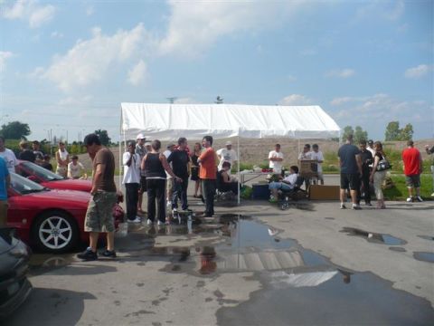 1993 Ford Probe - A group of people gather around a red 1993 Ford Probe at an outdoor event.