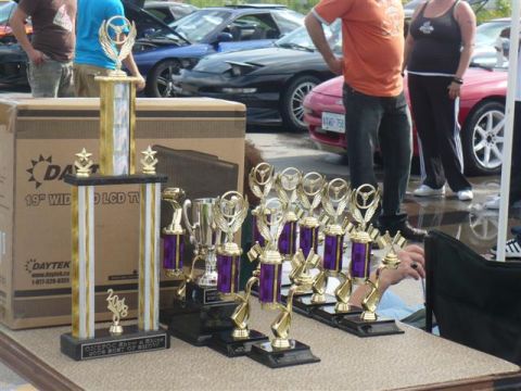 1993 Ford Probe - A collection of trophies sits in front of several cars, including a 1993 Ford Probe.