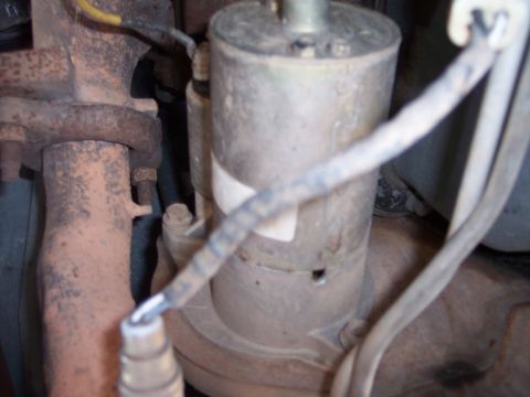 1996 Ford Bronco - A close-up view of a starter motor and exhaust pipe assembly, likely from a 1996 Ford Bronco, showing signs of rust and wear. Electrical wi…