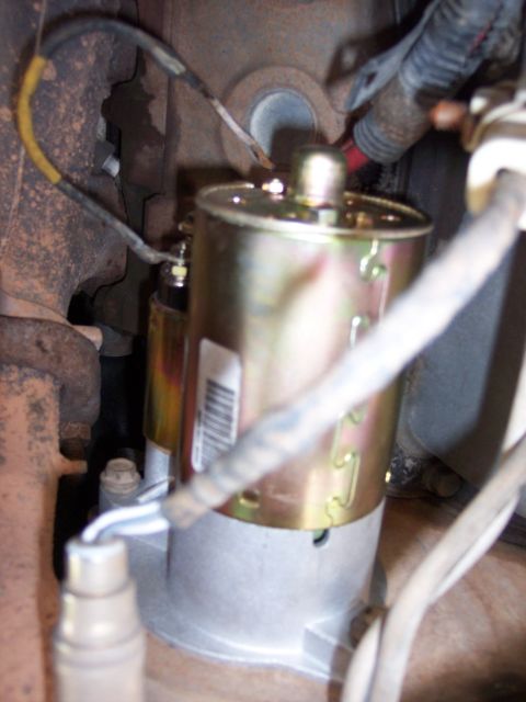 1996 Ford Bronco - Tight engine-bay shot of a newly installed starter motor with a gold zinc-plated housing, barcode label and cast aluminum nose, bolted agai…