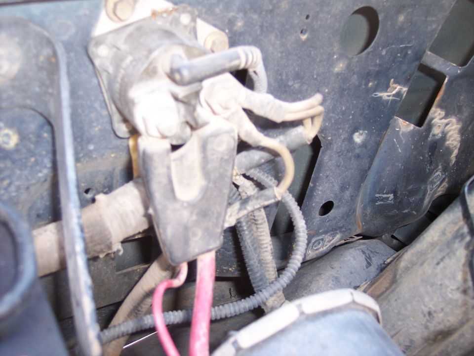Close-up of automotive wiring and a black plastic bracket holding pink and black wires.