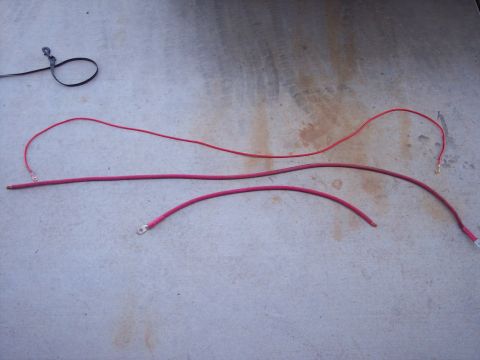 1996 Ford Bronco - Three red automotive battery cables and a black leash are laid out on a concrete surface.