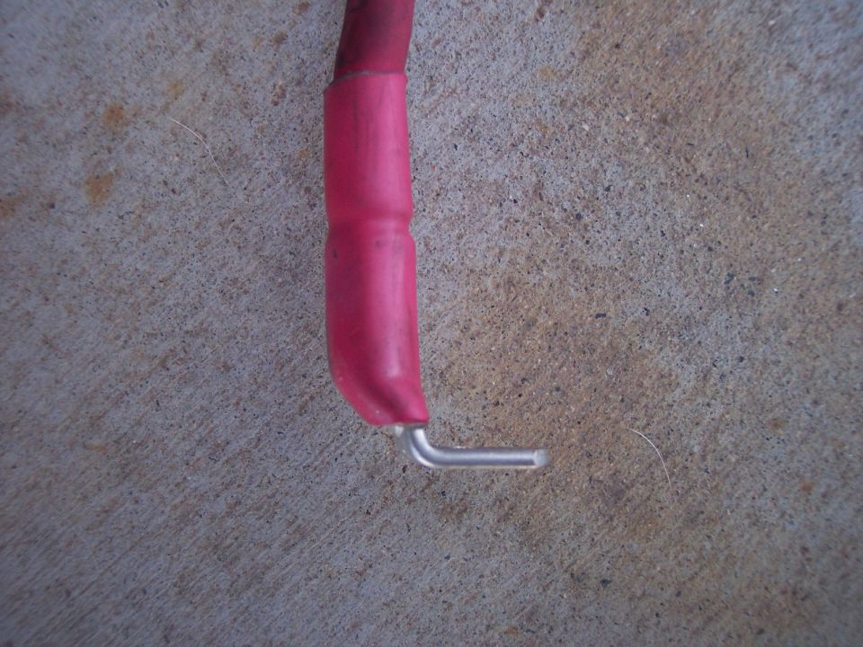 End of a red battery cable with heat-shrink tubing and a bent bare terminal pin
