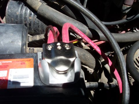 1996 Ford Bronco - Close-up view of the positive battery terminal on a 1996 Ford Bronco, showing red welding cables connected to the terminal clamp. The batte…