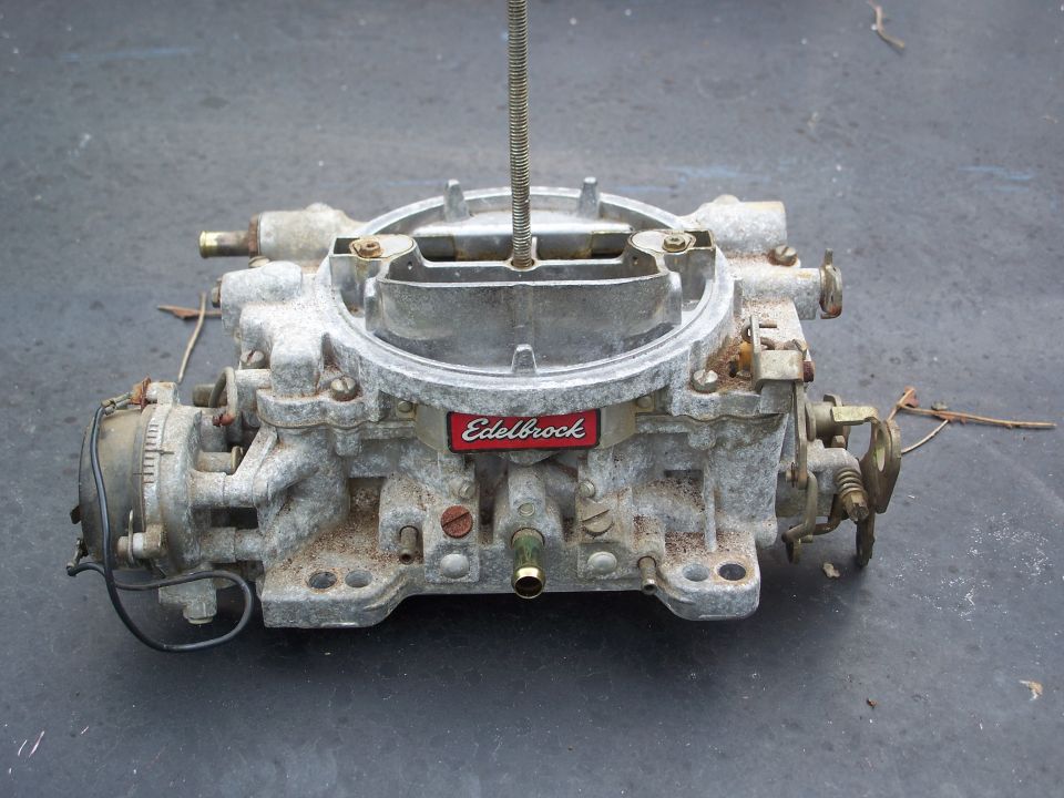 Used aluminum Edelbrock carburetor on a dark surface
