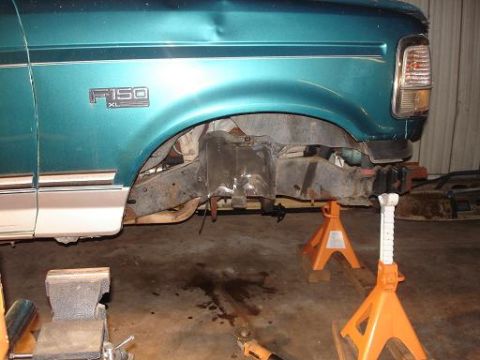 1996 Ford F-150 - The teal colored fender of a pickup truck is shown elevated on jack stands with the undercarriage exposed. The "F150 XL" emblem is visible…