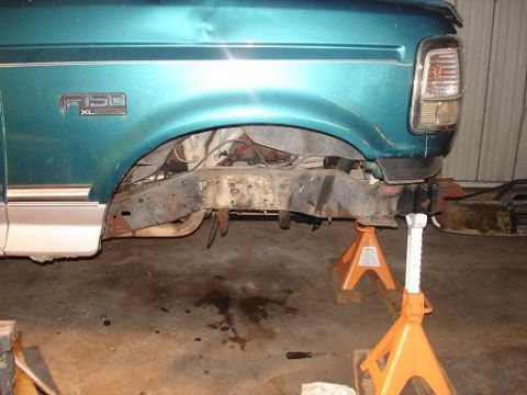 1996 Ford F-150 - The front driver's side of a teal Ford F-150 pickup truck is shown supported by orange jack stands. The front fender, wheel well, and part…