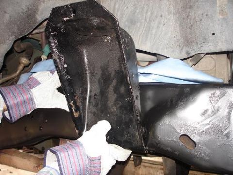 1996 Ford F-150 - Hands wearing work gloves hold a black metal bracket against the frame of a truck. The bracket is heavily textured and shows signs of wear…