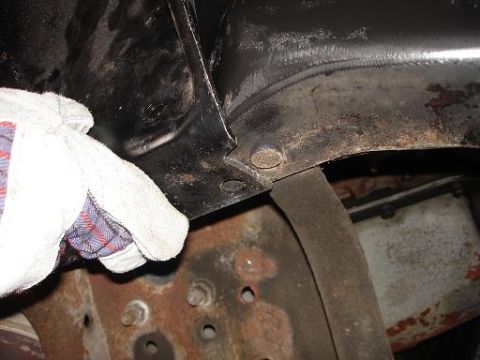 1996 Ford F-150 - A gloved hand is shown inspecting the underside of a vehicle, focusing on the frame and suspension components. The area appears to be rusty…