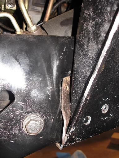 1996 Ford F-150 - A close-up view shows a metal bracket attached to a black painted vehicle frame. A bolt is visible on the left side of the frame, and a thi…
