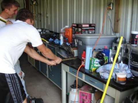 1996 Ford F-150 - Two men are working in what appears to be a garage or workshop. One man is holding a shovel and appears to be digging or moving something.