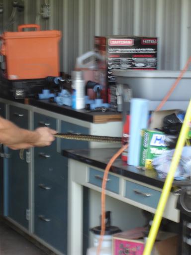 1996 Ford F-150 - A person's hand is holding a metal chain over a workbench with various tools and supplies.