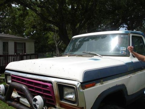 1996 Ford F-150 - Close-up front view of a white and blue Ford pickup truck with a pink grille and a brush guard. A person's arm is visible reaching towards…