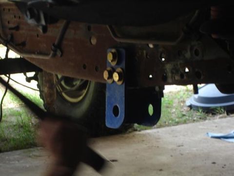 1996 Ford F-150 - A blue, U-shaped bracket with three large bolts is attached to the rusty frame of a vehicle. The bracket appears to be a modification, poss…