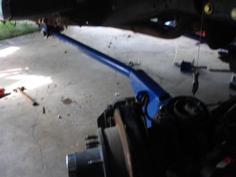 1996 Ford F-150 - A blue hydraulic jack is positioned under the frame of a vehicle, supporting a long blue metal bar that extends towards the front. The vehi…
