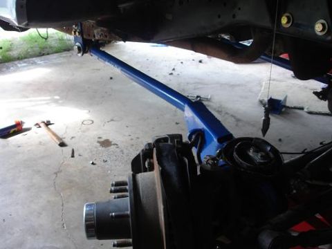 1996 Ford F-150 - A blue suspension component is attached to the underside of a vehicle frame, with a vehicle's brake rotor and hub assembly visible in the f…