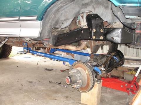 1996 Ford F-150 - The underside of a green Ford F-150 pickup truck is shown with the front suspension components removed and replaced with aftermarket blue t…