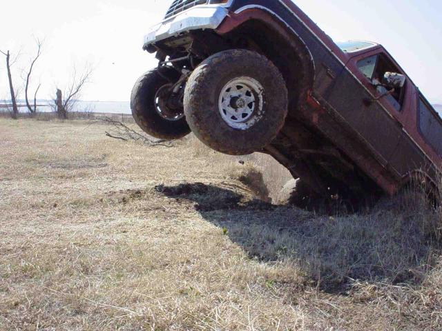 Red pickup truck tilted on its side off-roading