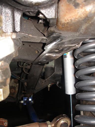 1996 Ford F-150 - The underside of a vehicle shows a suspension system with a silver shock absorber and a gray coil spring. A black leaf spring is visible ab…