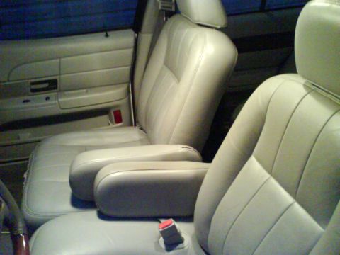 2003 Ford Crown Victoria - The interior of a light-colored vehicle shows the front seats, door panel, and part of the steering wheel. The seats appear to be leather w…
