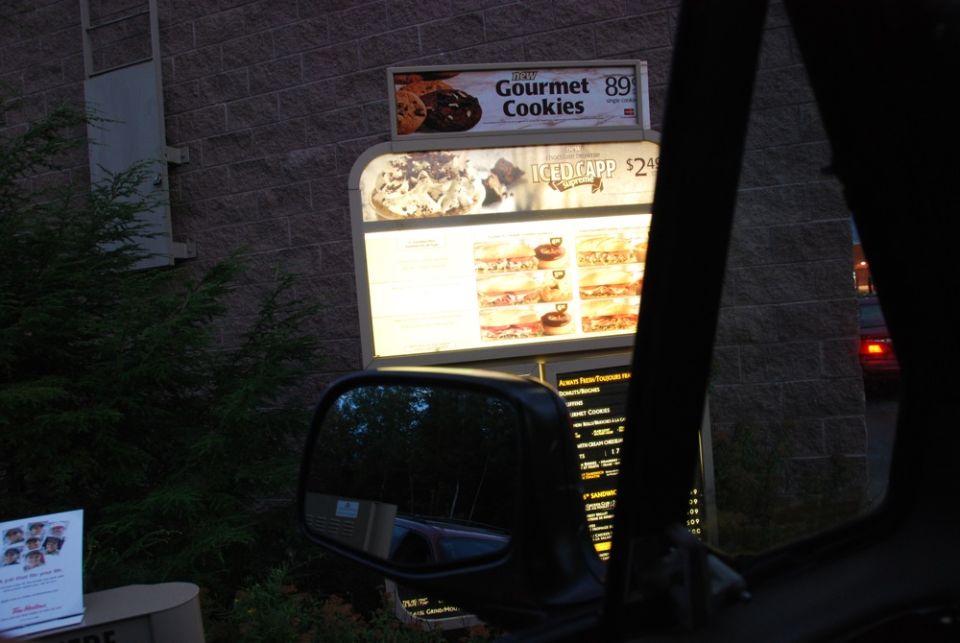 Drive-through menu board with cookies and iced coffee at dusk
