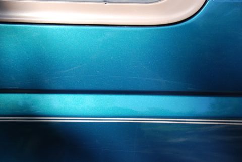 1996 Ford Bronco - Photograph of a teal painted body panel with chrome accent trim, not a technical document.