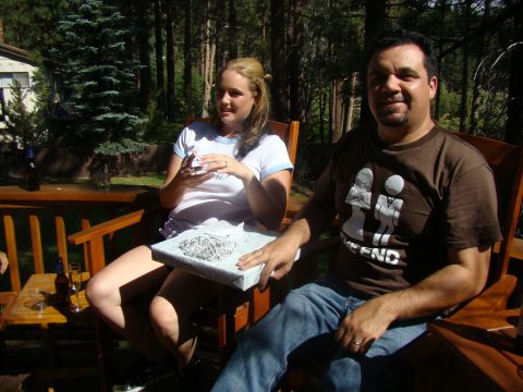 1989 Ford Bronco - A woman sits on a deck holding a wrapped gift, while a man sits next to her. They are outdoors in a wooded area.