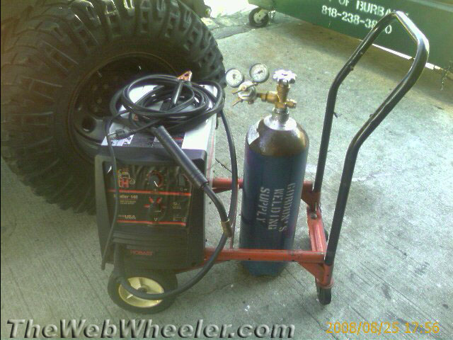 Hobart MIG welder and gas bottle on a red welding cart