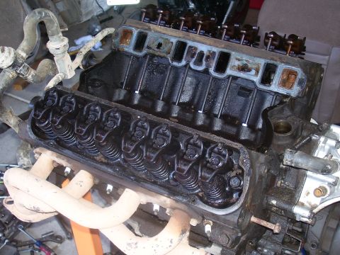 1991 Ford Bronco - A close-up view of a V8 engine block with the valve covers removed, revealing the rocker arms and valve springs. The exhaust manifolds are…