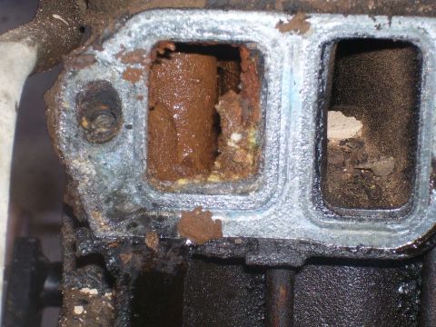 1991 Ford Bronco - A close-up view shows a heavily corroded and obstructed engine component, likely part of an exhaust manifold or intake system, with signifi…