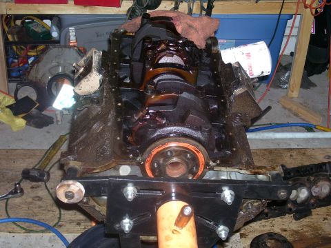 1991 Ford Bronco - A disassembled V8 engine block is mounted on an engine stand. Various engine components and tools are scattered around the workspace.