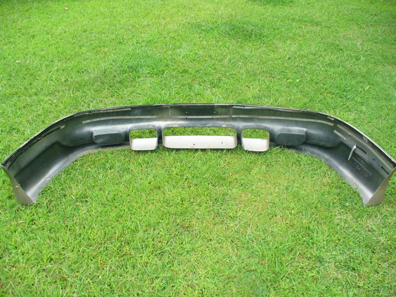 Removed dark green bumper cover face-down on grass with foam impact blocks