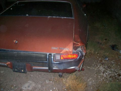1975 Ford Ranchero - The rear passenger side of a damaged, brown 1970s Ford Gran Torino is shown at night. The vehicle has significant damage to the rear quarte…